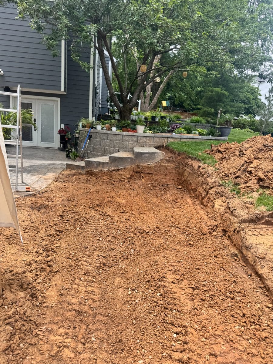 Trench excavated tight against a patio and retaining wall